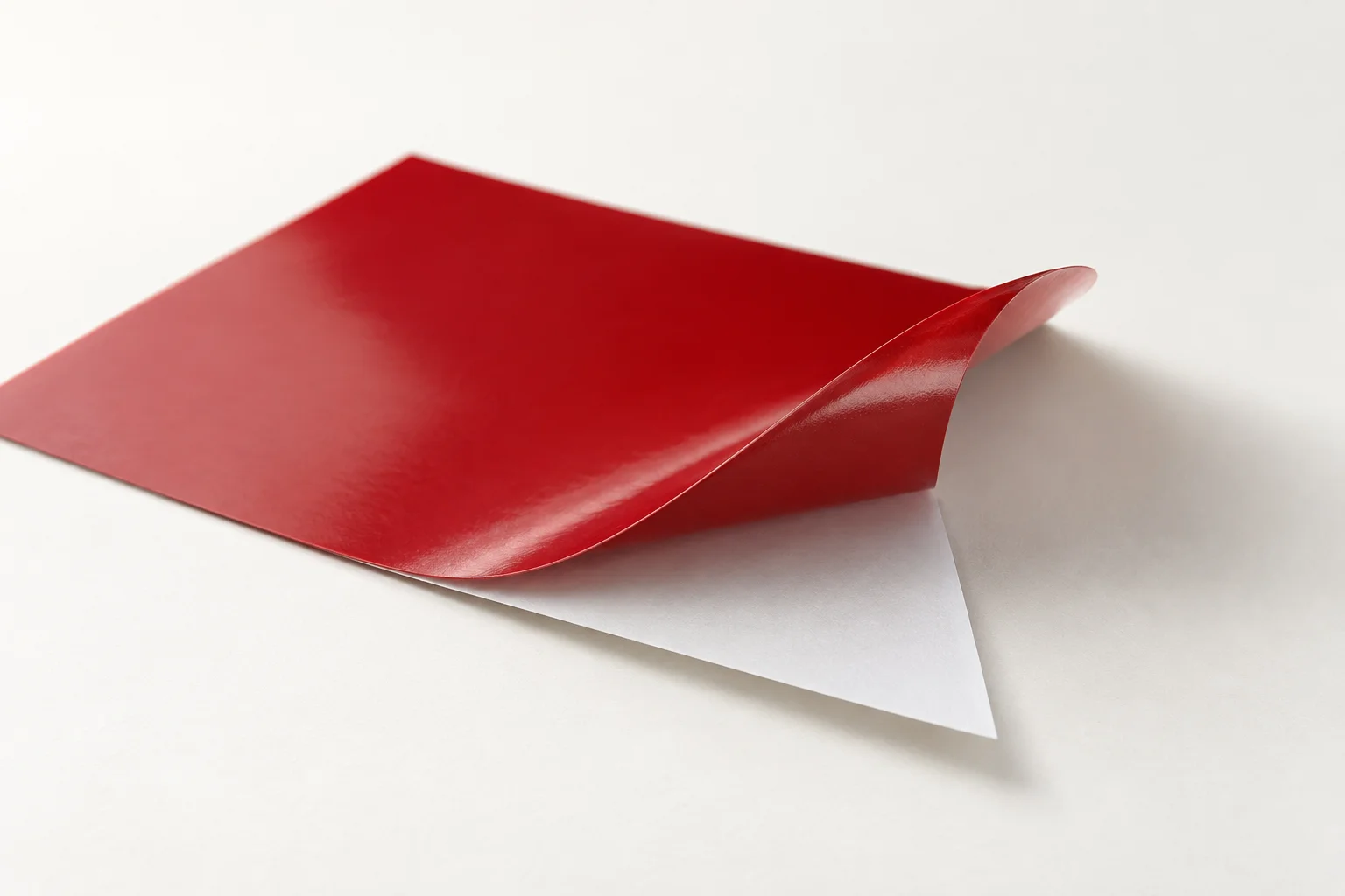 Thin red vinyl curling away from its white release-paper backing