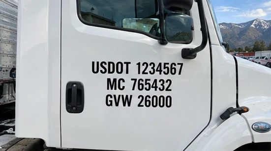 USDOT 1234567 MC 765432 GVW 26000 on a white truck door